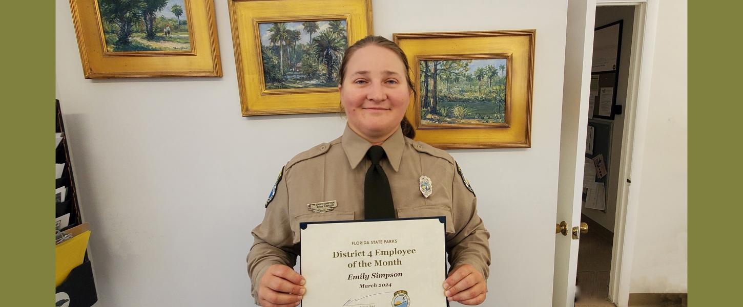 Park Ranger in uniform holding an award certificate.
